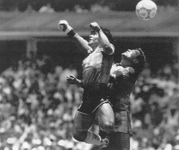 Maradona salta para dar um soco na bola e marcar um gol sobre a Inglaterra nas quartas-de-final da Copa do Mundo do México, em 1986. O episódio do gol ilegal validado pelo juiz ficou conhecido por 'A mão de Deus' — Foto: El Grafico via AP/Arquivo